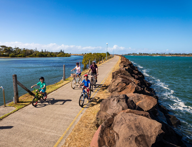 Family riding along break wall